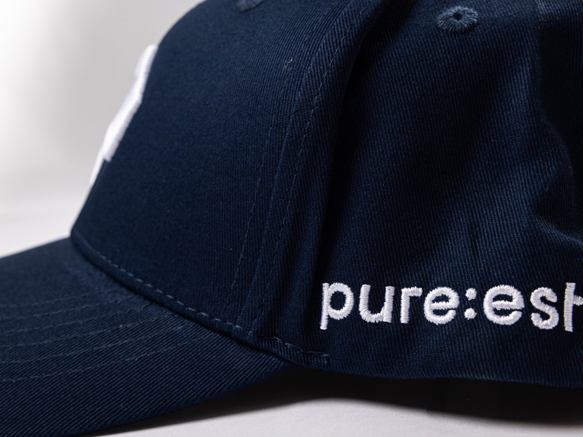 pureest keps. Broderad logo i vitt & mörkblå tyg